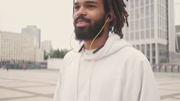 Молодий Оптимістичний Африканський Чоловік Виходить Вулицю Під Час Прослуховування Музики — стокове відео