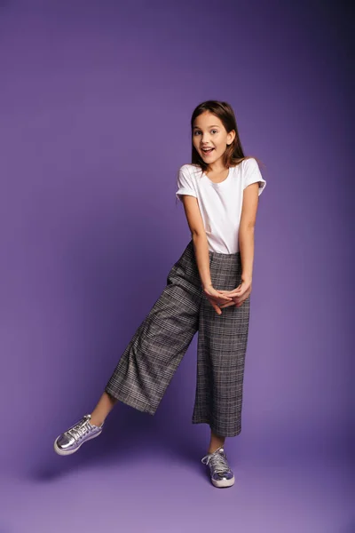 Full length photo of pleased caucasian girl smiling while dancing isolated over purple background