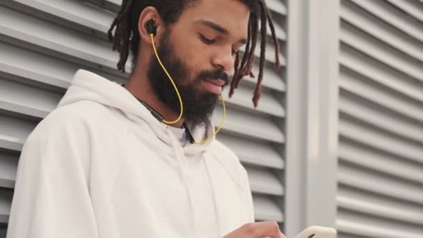 Joven Africano Concentrado Aire Libre Escuchando Música Por Auriculares Mientras — Vídeos de Stock