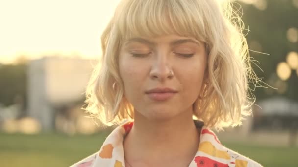 Гарненька Молода Блондинка Відкриває Очі Дивиться Камеру Під Час Прогулянки — стокове відео