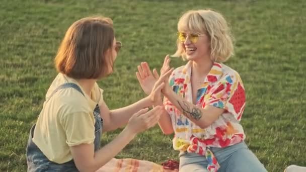Две Счастливые Девушки Веселятся Сидя Траве Парке — стоковое видео