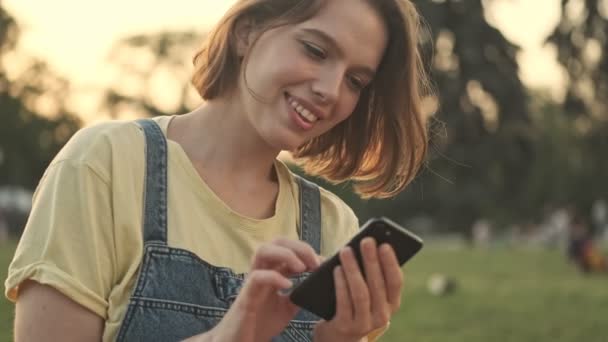 Vacker Ung Kvinna Använder Sin Smartphone När Hon Går Parken — Stockvideo