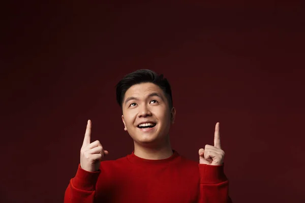 幸せな若いアジア人の男の画像笑顔と上向きブルゴーニュの背景に孤立指を指す — ストック写真