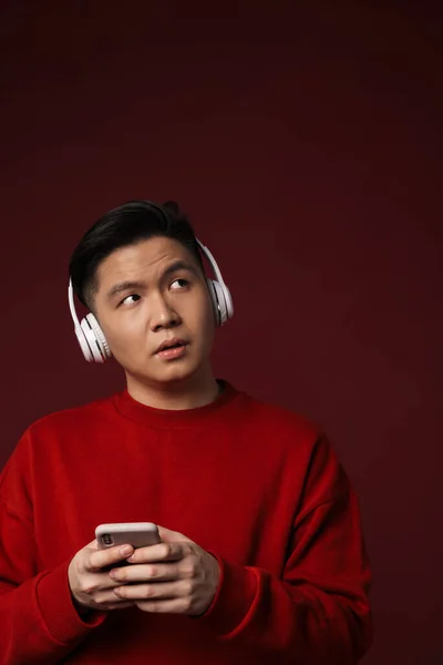 Imagen Hombre Asiático Guapo Pensando Usando Auriculares Teléfonos Celulares Aislados —  Fotos de Stock