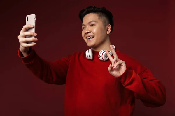 Image Joyful Asian Man Taking Selfie Cellphone Gesturing Peace Sign — Stock Photo, Image