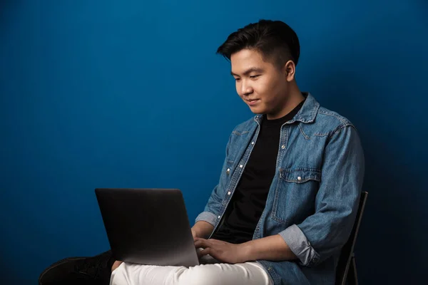 Imagen Hombre Asiático Guapo Complacido Usando Ordenador Portátil Mientras Está —  Fotos de Stock