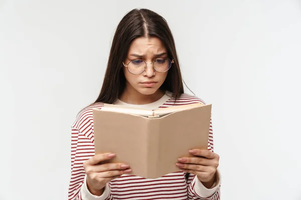 Zdjęcie Zdenerwowanej Brunetki Młodej Kobiety Noszącej Okulary Czytającej Książkę Białym — Zdjęcie stockowe