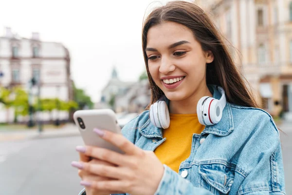 Imagen Encantadora Mujer Alegre Con Auriculares Inalámbricos Utilizando Teléfono Móvil — Foto de Stock