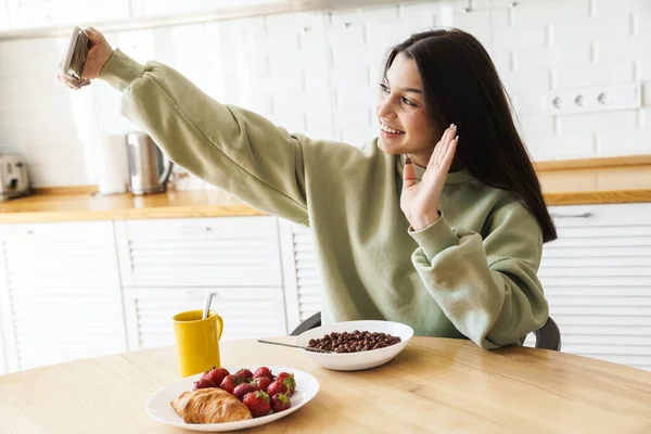Gülümseyen Kadının Cep Telefonuyla Selfie Çektiği Modern Mutfakta Kahvaltı Ederken — Stok fotoğraf