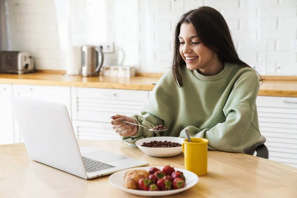 Foto Von Fröhlich Schöne Frau Mit Laptop Beim Frühstück Der — Stockfoto