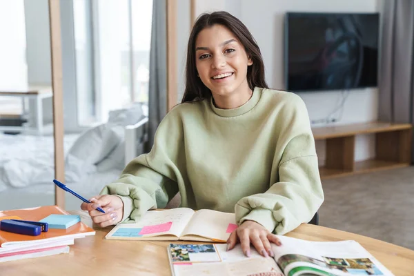 Foto Alegre Hermosa Estudiante Sonriendo Mientras Hace Tarea Sala Estar — Foto de Stock