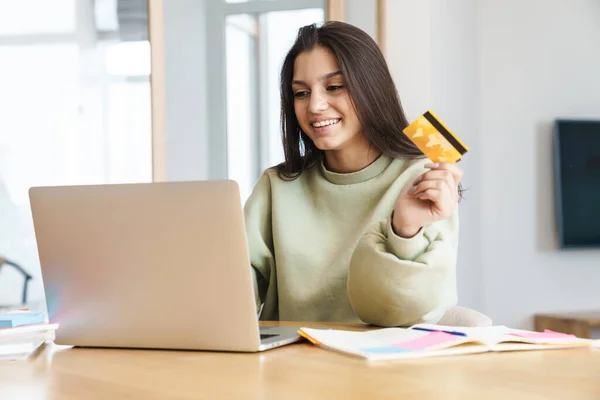 Foto Una Estudiante Bonita Alegre Sosteniendo Tarjeta Crédito Usando Ordenador —  Fotos de Stock