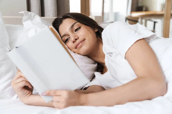 Foto Una Mujer Bastante Sonriente Leyendo Libro Mientras Está Acostada —  Fotos de Stock