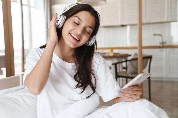 Foto Leende Vacker Kvinna Med Hjälp Mobiltelefon Och Trådlös Hörlurar — Stockfoto