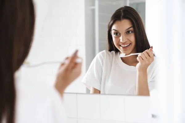 Foto Mulher Agradável Alegre Sorrindo Limpando Dentes Enquanto Olha Para — Fotografia de Stock