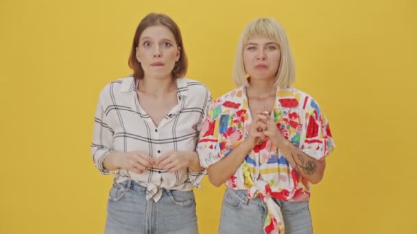 Två Koncentrerade Vackra Kvinnor Väntar Något Sedan Glädje Över Gul — Stockvideo