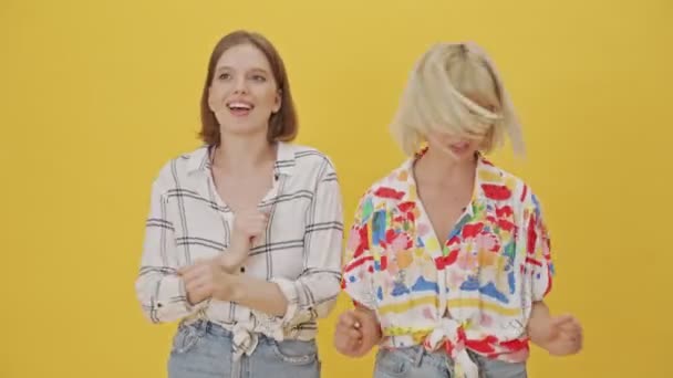 Twee Vrolijke Mooie Vrouwen Dansen Plezier Hebben Samen Gele Achtergrond — Stockvideo