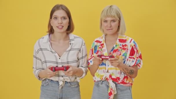 Two Happy Pretty Women Playing Video Games Joysticks Yellow Background — Stock Video