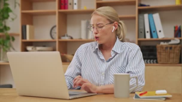 Μια Κουρασμένη Ξανθιά Επιχειρηματίας Ακουστικά Δουλεύει Τον Φορητό Υπολογιστή Της — Αρχείο Βίντεο