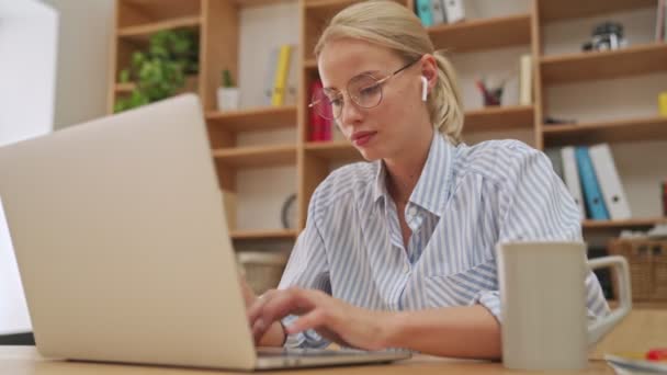 Šťastná Mladá Blondýnka Sluchátky Používá Svůj Notebook Sedí Kanceláři — Stock video