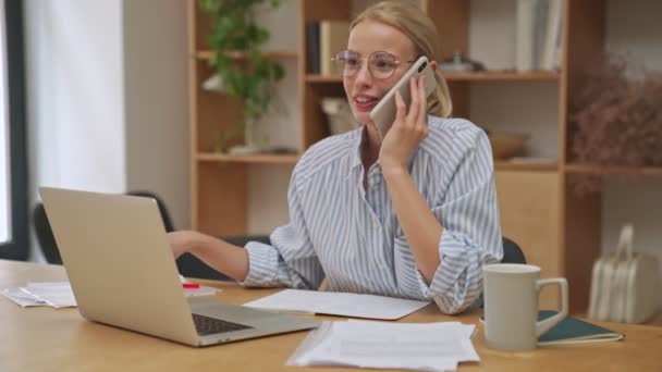 Šťastná Mladá Blondýnka Podnikatelka Mluví Telefonu Zatímco Pomocí Svého Notebooku — Stock video