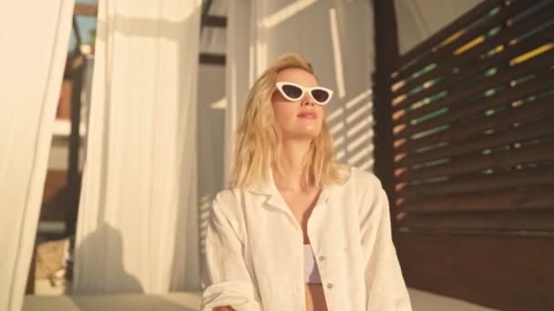 Una Hermosa Joven Rubia Con Gafas Sol Está Sentada Bungalow — Vídeos de Stock