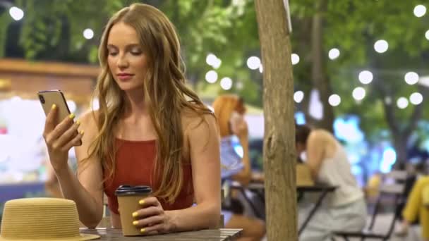 夏には都会の公園でコーヒーを飲みながら携帯電話を使っています — ストック動画