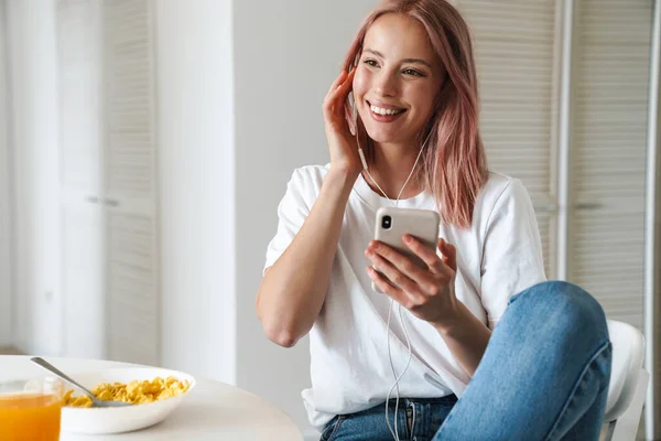 Fénykép Szép Vidám Használja Mobiltelefon Fülhallgató Miközben Reggeli Fehér Konyhában — Stock Fotó