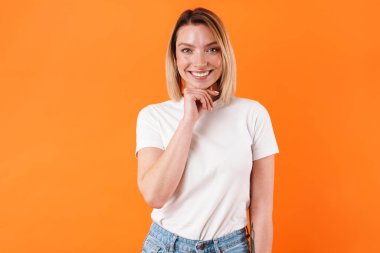 Turuncu arka planda izole edilmiş gülümseyen ve kameraya bakan mutlu beyaz kadın görüntüsü