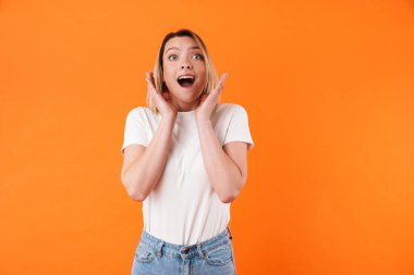Heyecanlı beyaz kadın görüntüsü turuncu arka planda izole edilmiş kamerada şaşkınlığını ifade ediyor.