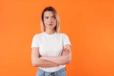 Elleri çapraz pozlarda turuncu arka planda poz veren güzel bir kadın.