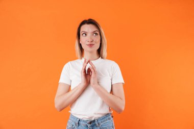 Portakal rengi arka planda hayal kuran ve yukarı bakan mutlu çekici bir kadın görüntüsü