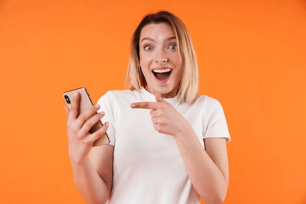 Image Delighted Woman Holding Pointing Finger Mobile Phone Isolated Orange — Stock Photo, Image