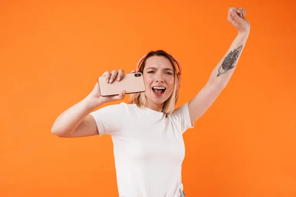 Image Excited Young Woman Singing Using Cellphone Headphones Isolated Orange — Stock Photo, Image