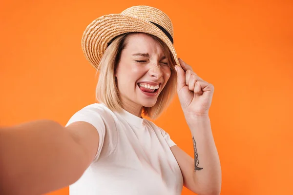 照片中戴草帽快乐的年轻女子笑着 在橙色背景下自拍 — 图库照片
