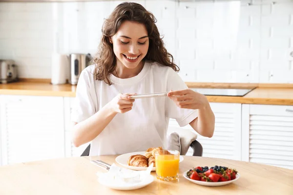Mutfakta Kahvaltı Yaparken Gülümseyen Cep Telefonuyla Fotoğraf Çeken Neşeli Bir — Stok fotoğraf