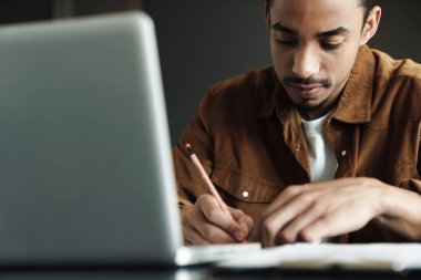 Afro-Amerikan bir adamın oturma odasında çalışırken dizüstü bilgisayar kullanması düşüncesi.