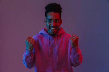 Mutlu Afro-Amerikan portresi renkli kapüşonlu adam menekşe arka planda izole edilmiş başarıyı kutluyor