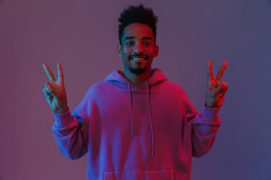 Afro-Amerikan renkli kapüşonlu adamın portresi. Gülümsüyor ve barış şarkıları söylüyor. Menekşe arka planında izole bir şekilde.