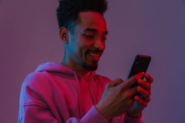 Siyahi kapüşonlu genç Afrikalı Amerikalı adamın portresi Violet 'in arka planından izole edilmiş bir cep telefonuyla video görüşmesi yapıyor.