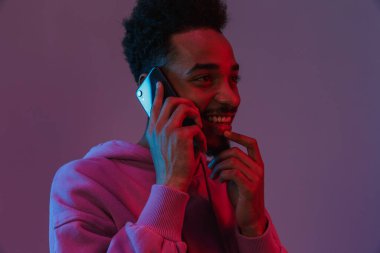 Siyahi kapüşonlu gülen Amerikalı adamın portresi Violet 'in arka planından izole edilmiş cep telefonuyla konuşuyor.