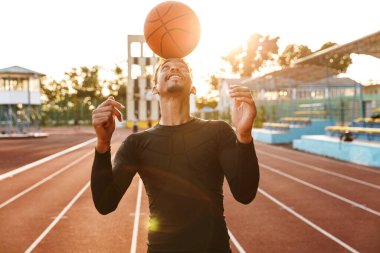 Afrikalı, güçlü, pozitif, genç bir sporcunun stadyumdaki fotoğrafı basketbol oynuyor..