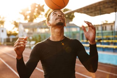 Stadyumda basketbol oynayan Afrikalı yakışıklı genç bir adamın görüntüsü..