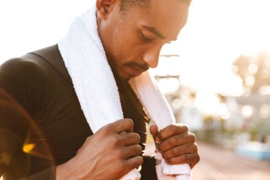 Ciddi bir Afrikalı Amerikalının spor sahasında havluyla koşması.