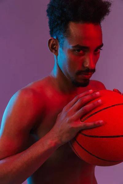 年轻的无运动上衣的非洲裔美国男子与篮球隔离在紫色背景下的肖像 — 图库照片