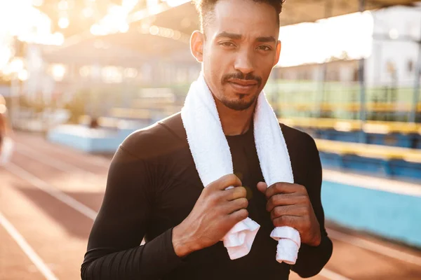 一个英俊的非洲裔美国人拿着毛巾站在运动场跑道上的形象 — 图库照片