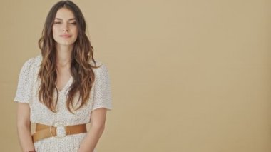 Pozitif bir genç kadın, stüdyoda bej bir arka plan üzerinde duran bir tarafı işaret ediyor.