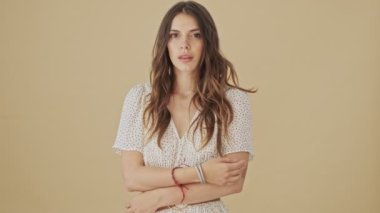 Pozitif genç bir bayan stüdyoda bej bir geçmişin başında gizli bir jest yapıyor.