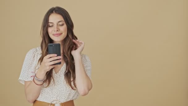 Een Glimlachende Jonge Vrouw Gebruikt Haar Smartphone Die Een Beige — Stockvideo