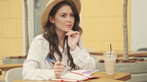 Χαμογελώντας Ελκυστική Γυναίκα Φορώντας Καπέλο Σκέφτεται Κάτι Και Γράφοντας Στο — Αρχείο Βίντεο